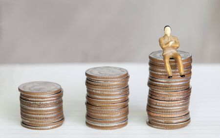 Figure miniature businessman or small people sit on money coin and book background for money and financial business shopping concept.の写真素材