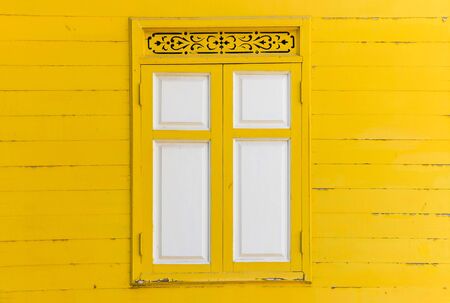 yellow peeling painted on wooden wall with white window, textures background, cracked paintの写真素材