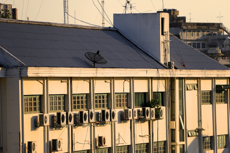 building wall with many air conditioners and parabolic satellite dishes on the rooftopsの写真素材