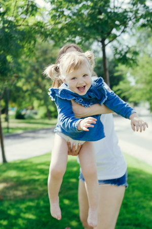 Portrait of a young mother and her 3 years old daughter playing in a city park on a warm sunny dayの写真素材