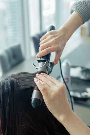 Hairdresser straightening models hair in a beauty salonの写真素材