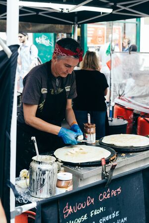 London/UK - July 20 2018: woman making savoury crepes with hazelnut cocoa spread and bananas on Portobello market, London, UKのeditorial素材