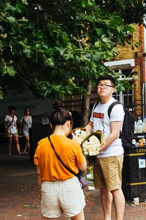 London/UK - July 22 2018: Asian woman photographing flowers purchased on the Columbia flower market in Londonのeditorial素材