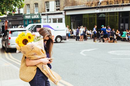 London/UK - July 22 2018: Young woman with bunch of flowers purchased on the Columbia Road Flower Market in the East of London, UKのeditorial素材