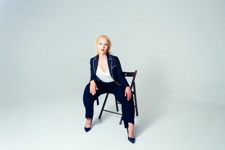 Studio portrait of beautiful blond woman in a black dress against white plain backgroundの写真素材