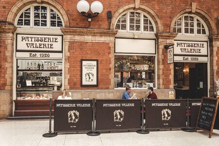 London/UK - 22/07/2019: men talking at the Patisserie Valerie sitting area just outside the cafe which is inside the Marylebone Station. Patisserie Valerie is a chain of cafÃ©s operates in the UKのeditorial素材