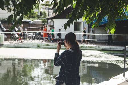 London/UK - 22/07/2019: Asian girl is taking a photo near Paddington Canal in Little Venice, London's district around the junction of the Paddington Arm of the Grand Union Canal and the Regent's Canalのeditorial素材