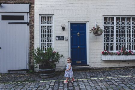 London/UK - 22/07/19: toddler walking past the blue door of the mews house in Bayswater, an affluent...