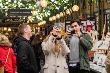 London / UK - Nov 24, 2019: young men photographing Christmas decorations in the Apple market in Covent Garden, London, UKのeditorial素材