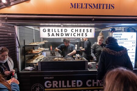 London / UK - Nov 24, 2019: people walking past the Meltsmiths Grilled Cheese Sandwiches stall at...