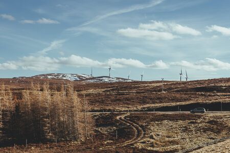 An onshore wind farm in the Scottish Highlands. A group of wind turbines in the same location used to produce electricityの写真素材