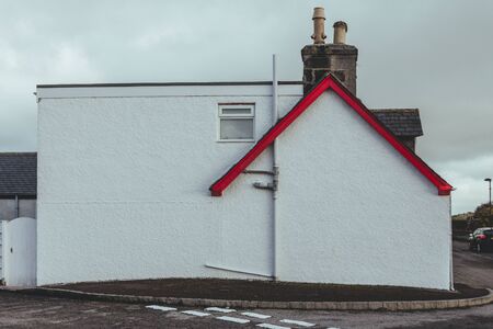 White wall of a typical terraced house in the UK with red painted roof and chimneyの写真素材