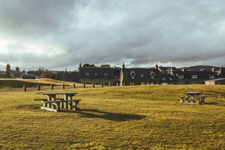 Picnic area with tables on a hill in the Brora village, Scotland, on the sunset. Typical terraced...