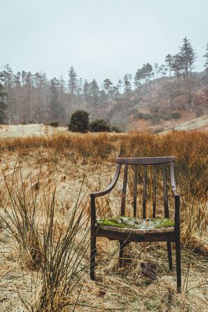Old broken rustic chair left in the field in the last year grass in Scotland