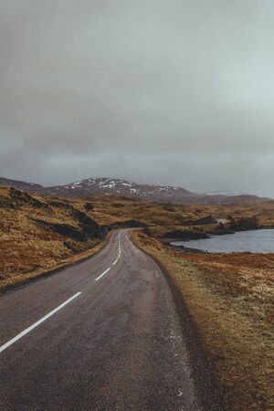Scenic view of a road along the lake in a valley in Scottish highlandsの写真素材