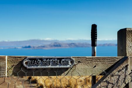 Wooden gates in the hills of Scotland with metal plate warning to keep them shutの写真素材