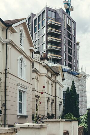 Concept photo of an old Georgian architecture style white stucco terraced houses and a new...
