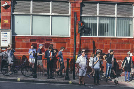 London/UK-1/08/18: people standing on a crossroad on Hampstead High Street, waiting for a green...