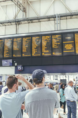 London/UK-1/8/19:young men waiting for their train at the London Waterloo station in a rush-hour. Central London terminus on the National Rail network in the UK, located in the Waterloo area,  Lambethのeditorial素材