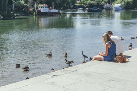 London/UK-1/08/18: young couple sitting on Buccleuch Passage on the embankment of the River Thames...