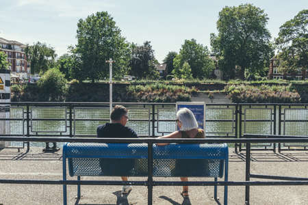 London/UK-1/08/18: Senior couple sitting on a bench on Buccleuch Passage on the Thames riverside in Richmond. Happy relationships and togetherness conceptのeditorial素材