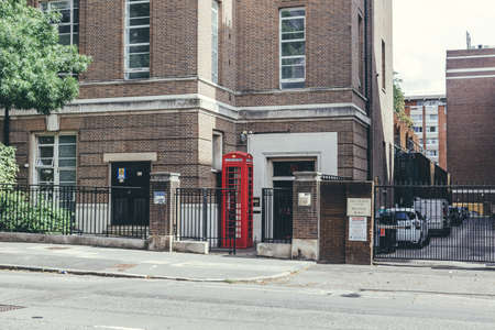 London/UK-30/7/18: enormously tall red telephone box on a London street. Modern art concept. Despite...