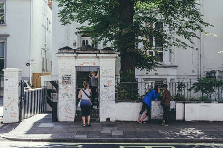 London/UK-30/7/18: tourists writing graffiti on the wall of the Abbey Road Shop next to the namesake...