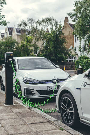 London/UK-30/07/18: two white Volkswagen Golf GTE cars charging at a charging point on a street in...