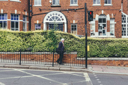 London/UK-30/7/18: an older gentleman in a classic dark blue suit walking to the pedestrian crossing...