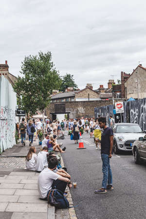 London/UK - 22/07/18: young people resting on a sidewalk on a warm summer day on Ezra Street next to Columbia Street where the famous flower market taking placeのeditorial素材