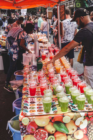London/UK - 22/07/18: man buying freshly prepared fruit smoothie in a stall on the Brick Lane Market. Brick Lane Market is a London market centered on Brick Lane, in Tower Hamlets in east Londonのeditorial素材