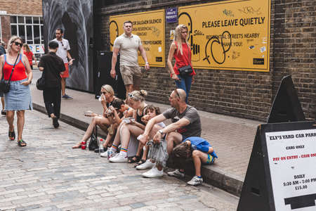 London/UK - 22/07/18: Mother, father, daughter and 3 sons sitting on the side of a road in Ely's...