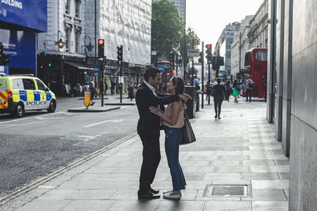 London/UK-24/07/18: a young couple, man and woman, looking at each other, smiling and embracing on a street in London on a warm sunny day; selective focusのeditorial素材