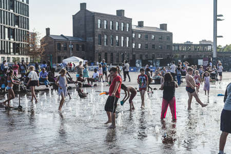 London/UK-26/07/18: kids playing in the fountain on Granary Square on a hot summer day. The fountain consisting of 1,080 jets rising from the flush paved surface of the plaza; selective focusのeditorial素材