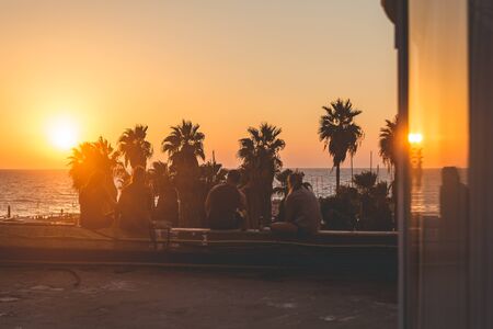 People seeing off the sunset over the Mediterranean Sea on the promenade in Tel Aviv on a warm summer eveningの写真素材