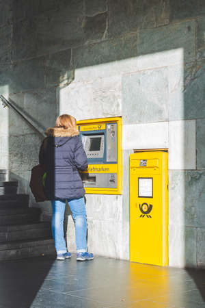 Bamberg/Germany-2/1/19: rear view of a woman withdrawing cash in the ATM of Deutsche Postbank on a street in a german town. Postbank is the retail banking division of Deutsche Bankのeditorial素材
