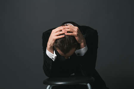 Portrait of a young caucasian man in a tuxedo with hands in his hairの写真素材