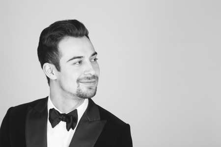 Studio portrait of a young caucasian man in a tuxedo, looking to the side, against plain studio backgroundの写真素材