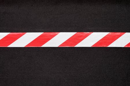 Red and white warning tape on the black carpet.の写真素材
