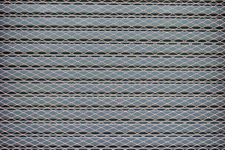 Wire mesh fence on a background of gray steel doors