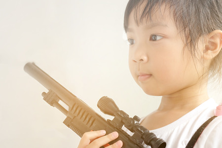 Asian child girl holding a gun filled with emotional commitment.の写真素材