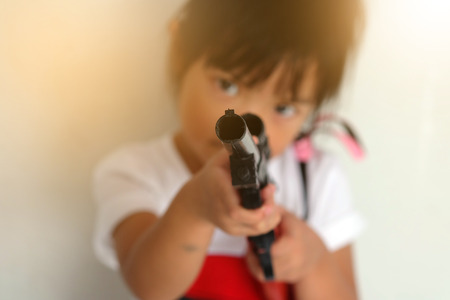Asian child girl holding a gun filled with emotional commitment.の写真素材