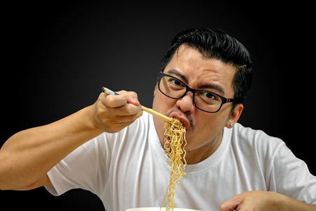Asian man eating Instant noodles isolated on black background, with clipping pathの写真素材