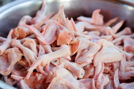 Raw chicken legs and chicken wings in a large stainless steel basinの写真素材