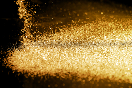 Sprinkle gold dust on a black background with copy space.の写真素材