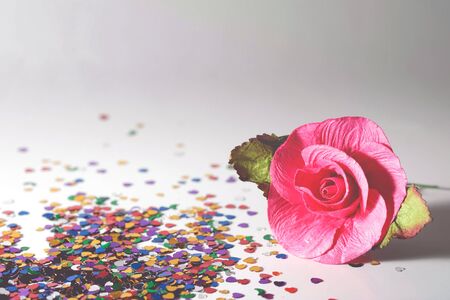 Artificial pink roses on a gray background with heart colorful glitterの写真素材