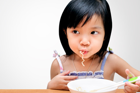 Asian child girl eating Instant noodles isolated on white background, with clipping pathの写真素材