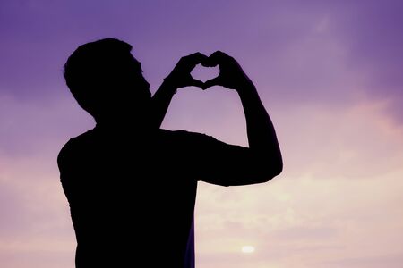 Silhouette of Man  hand a heart symbol, A symbol of peace or love, Sweet toneの写真素材