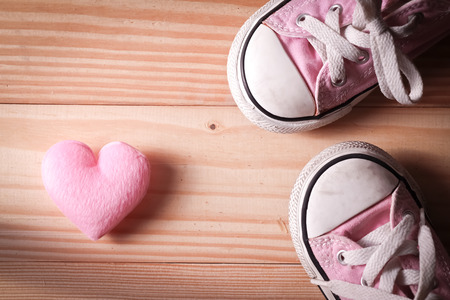 Pink girl's sneakers with pink hearts on a wooden floor, The concept of Valentine's Day.の写真素材