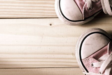 Pink girl sneakers on a wooden floor with copy spaceの写真素材
